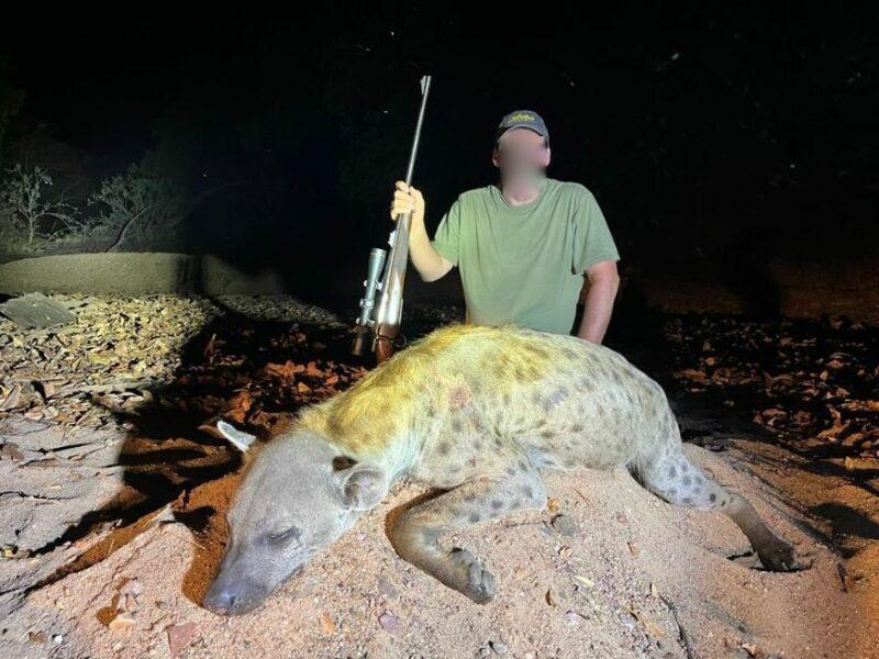man posing with trophy hyena