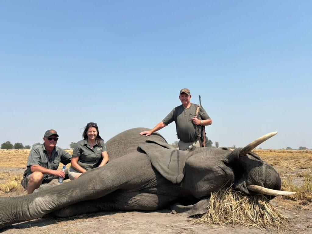 Three people posing next to an elephant that has just been shot.