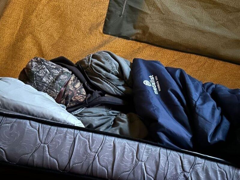 Man lying in sleeping bag, covered against the cold