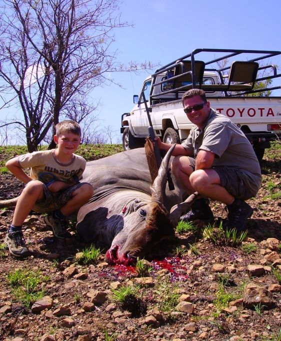 A hunter and his son posing with an eland