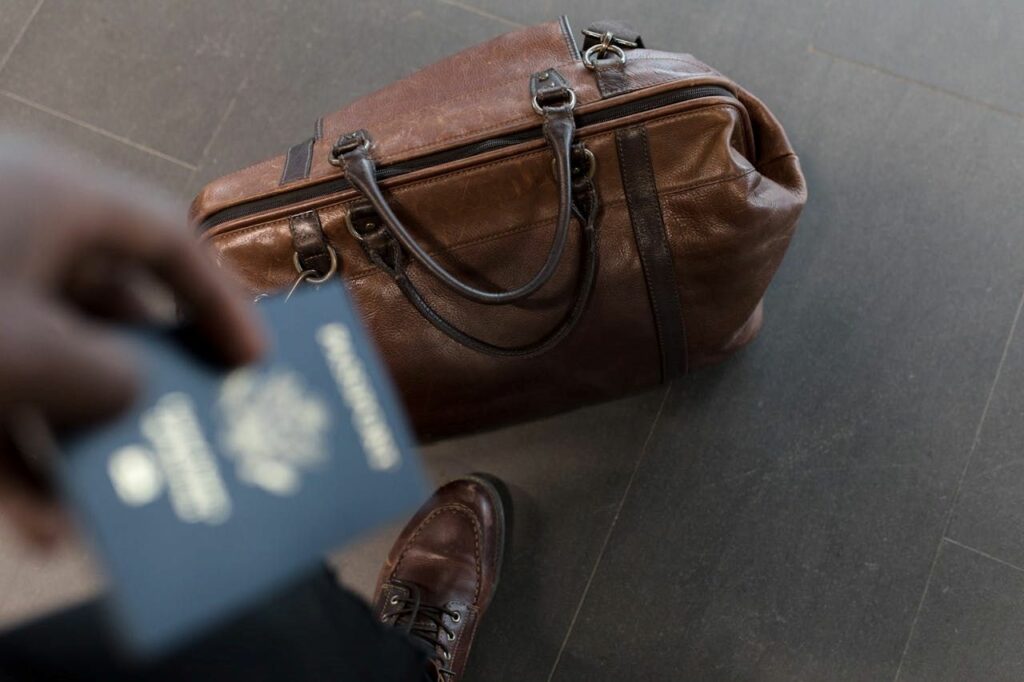 Hand holding passport with bag on the ground