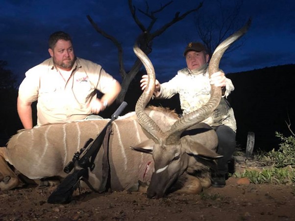 Two men posing in the dark, with a trophy kudu bull.